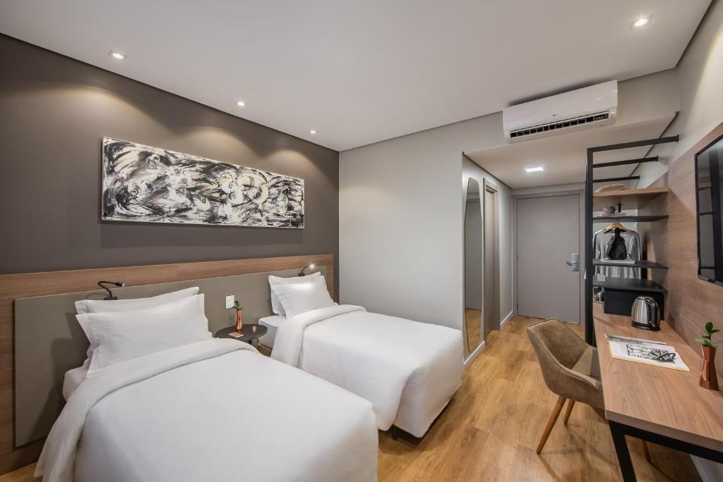 um quarto de hotel com duas camas e uma secretária em Intercity Sao Leopoldo em São Leopoldo