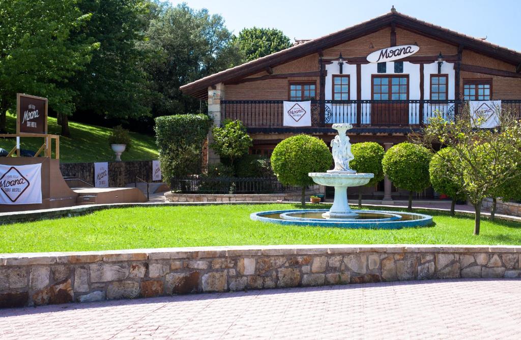 a fountain in the grass in front of a building at Moana Surf Hostel in Urduliz