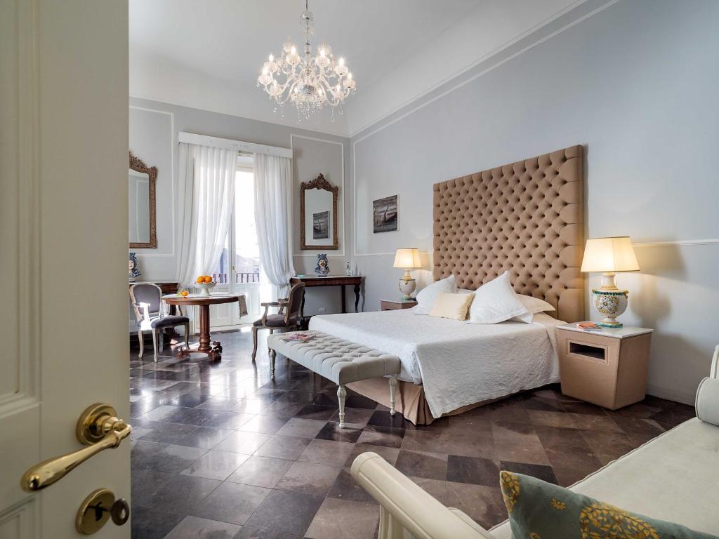 een slaapkamer met een groot bed en een kroonluchter bij Gagliardi Boutique Hotel in Noto