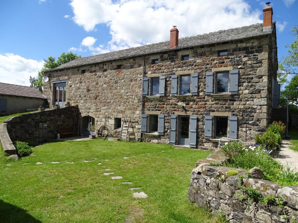 una vieja casa de piedra con un patio delante en La Ferme de Madelonnet, en Saint-Jeures