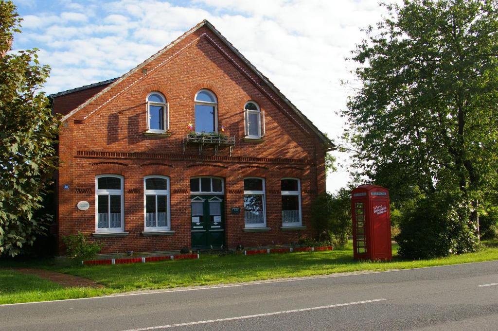 a brick house with a red phone booth in front of it at Das Haus mit der roten Telefonzelle in Apen