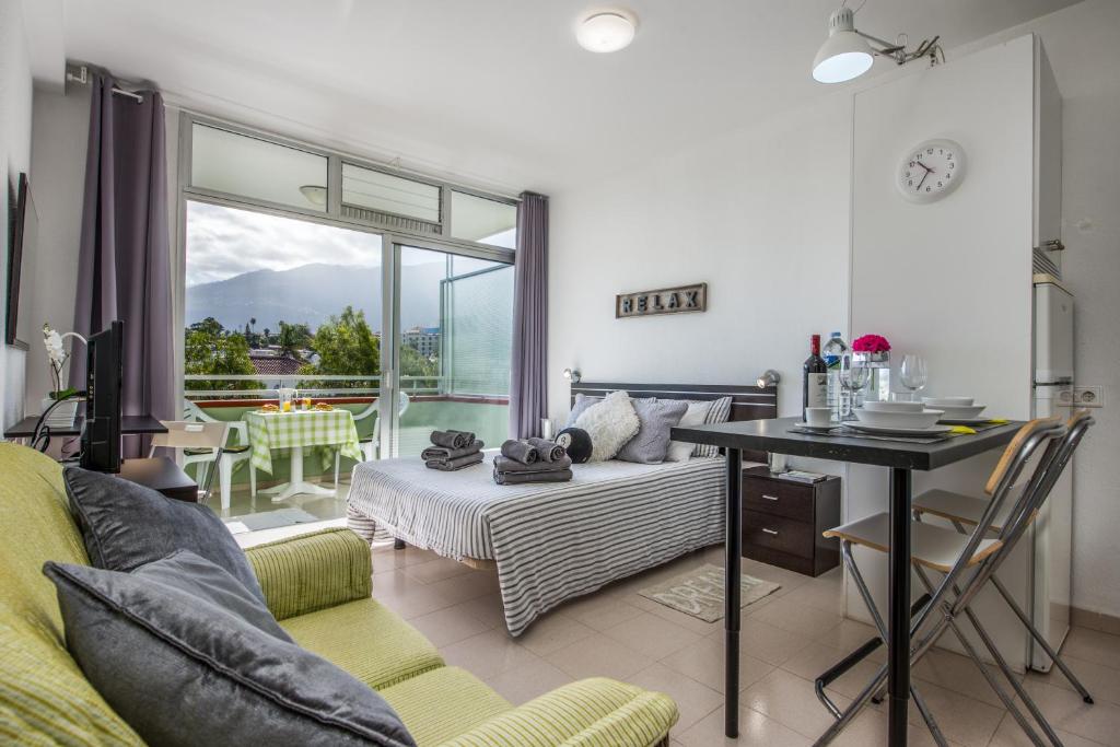 ein Wohnzimmer mit einem Bett und einem Tisch sowie einem Balkon in der Unterkunft Apartamentos Estudio Nuevo en Puerto de la Cruz in Puerto de la Cruz
