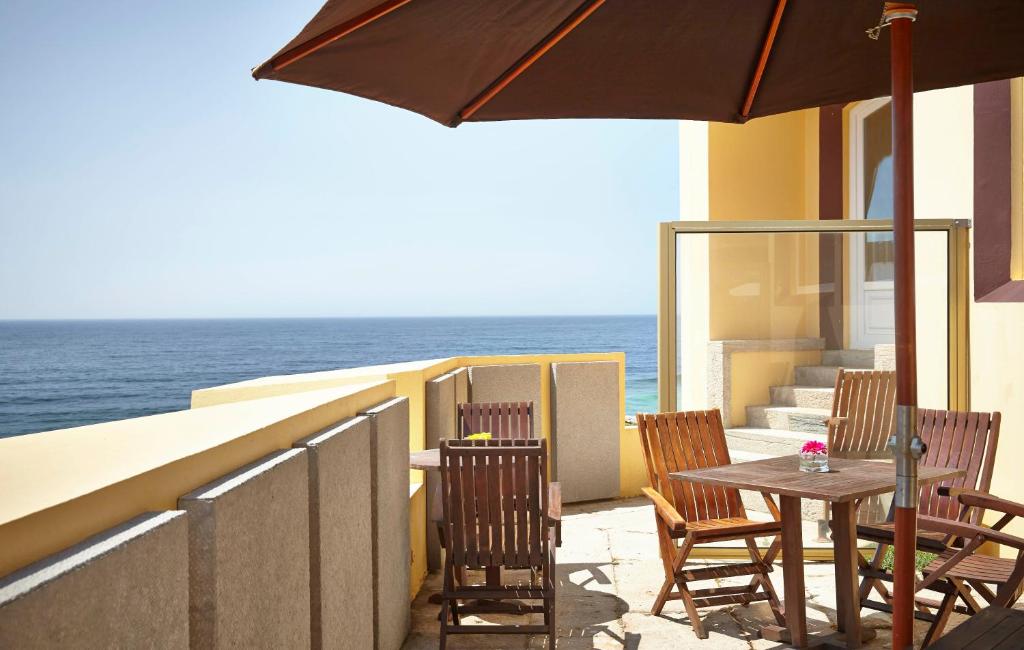 a patio with chairs and a table with an umbrella at Hotel Fortaleza do Guincho Relais & Châteaux in Cascais