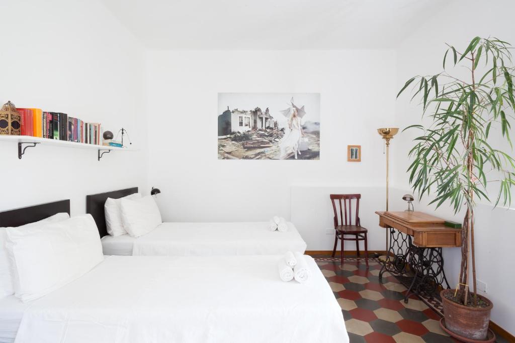 een slaapkamer met 2 bedden en een potplant bij Buonocore Guesthouse in Bergamo