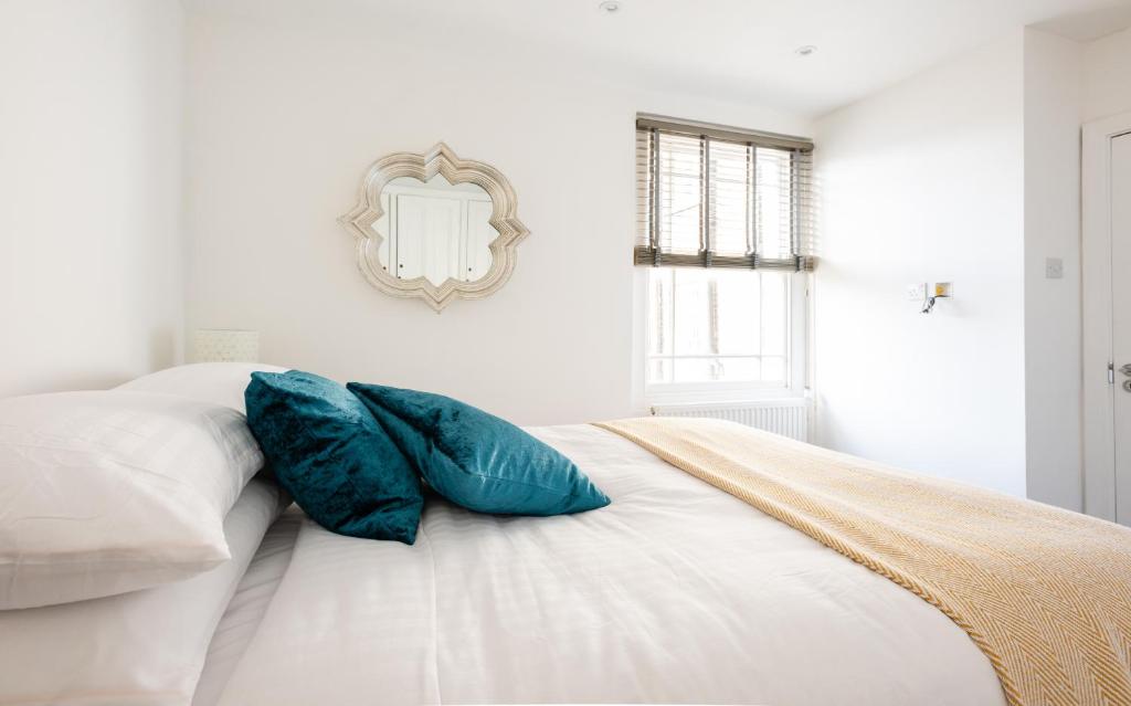 a white bed with two blue pillows on it at The Marylebone Residence in London