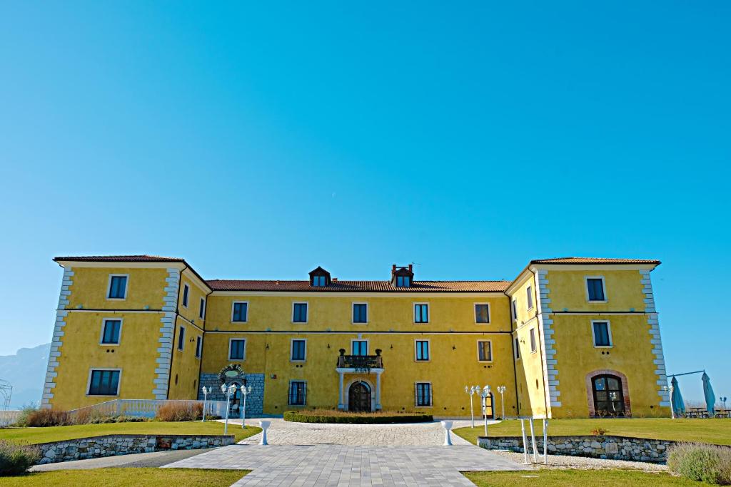 un gran edificio amarillo con un cielo azul en el fondo en Eliceto Resort & SPA, en Buccino
