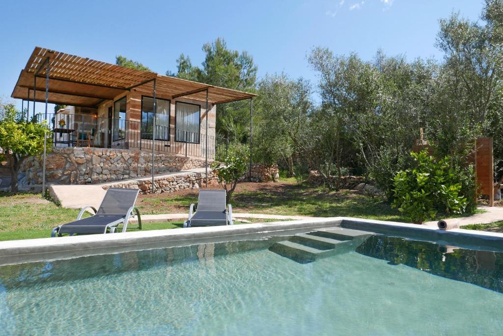 une piscine avec deux chaises et une maison dans l'établissement Es Mirador - Adults Only, à Manacor