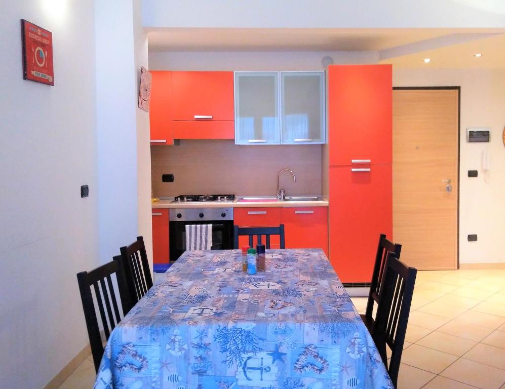 kuchnia ze stołem z krzesłami i czerwonymi szafkami w obiekcie Appartamento Angela w mieście Pietra Ligure