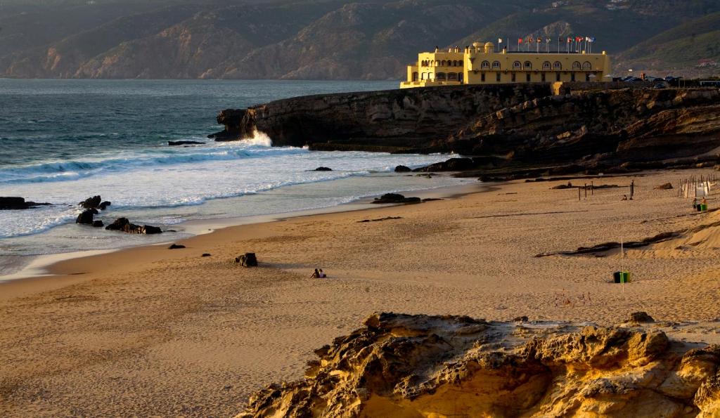 a beach with a building on top of a cliff at Hotel Fortaleza do Guincho Relais & Châteaux in Cascais