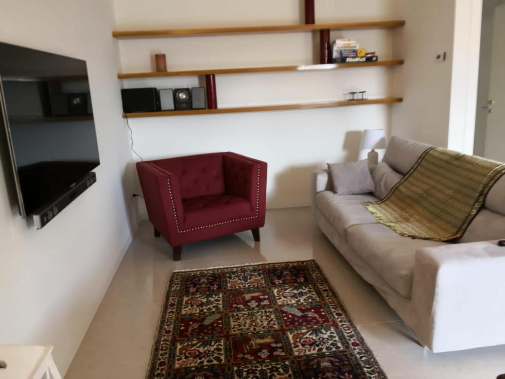 uma sala de estar com um sofá e uma cadeira vermelha em Appartamento nel Cuore della Valpolicella em San Pietro in Cariano