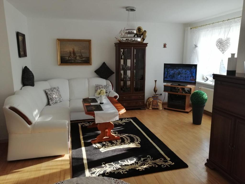 a living room with a white couch and a tv at Apartament Paradise in Międzyzdroje