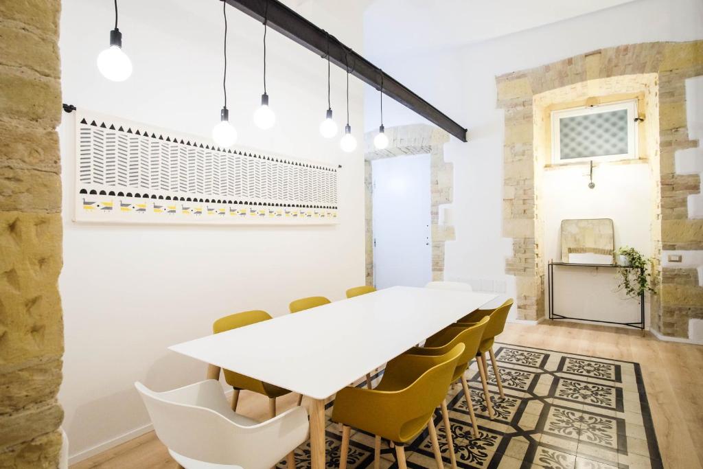 ein Esszimmer mit einem weißen Tisch und gelben Stühlen in der Unterkunft Orma Design Rooms - Historic centre in Cagliari