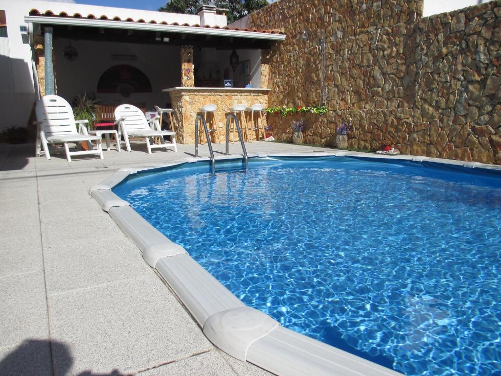 a swimming pool in a yard with chairs and a stone wall at Casa da Boa Agua 1 in Quinta do Conde