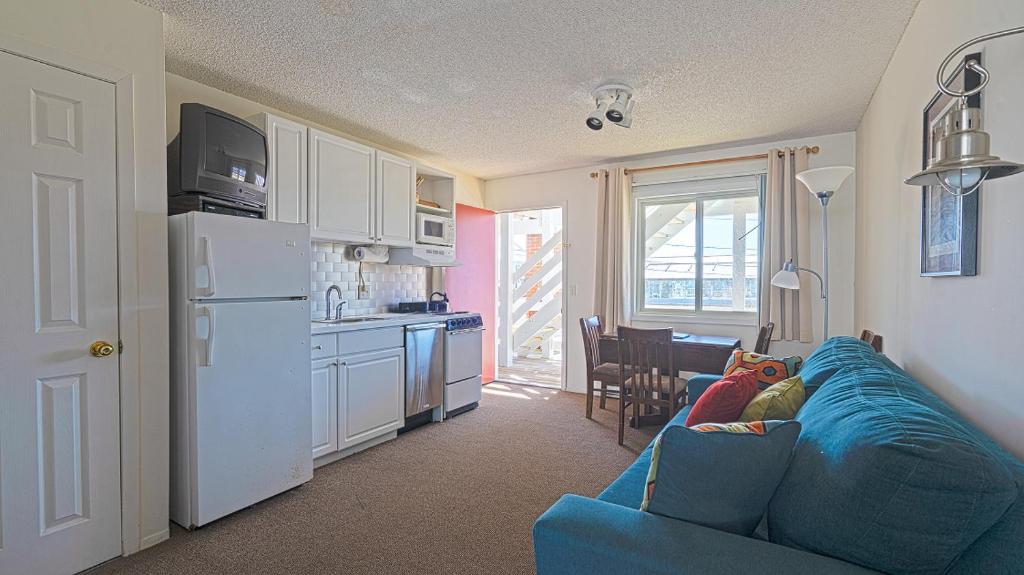 a living room with a blue couch and a kitchen at Montauk Oceanside Suites in Montauk