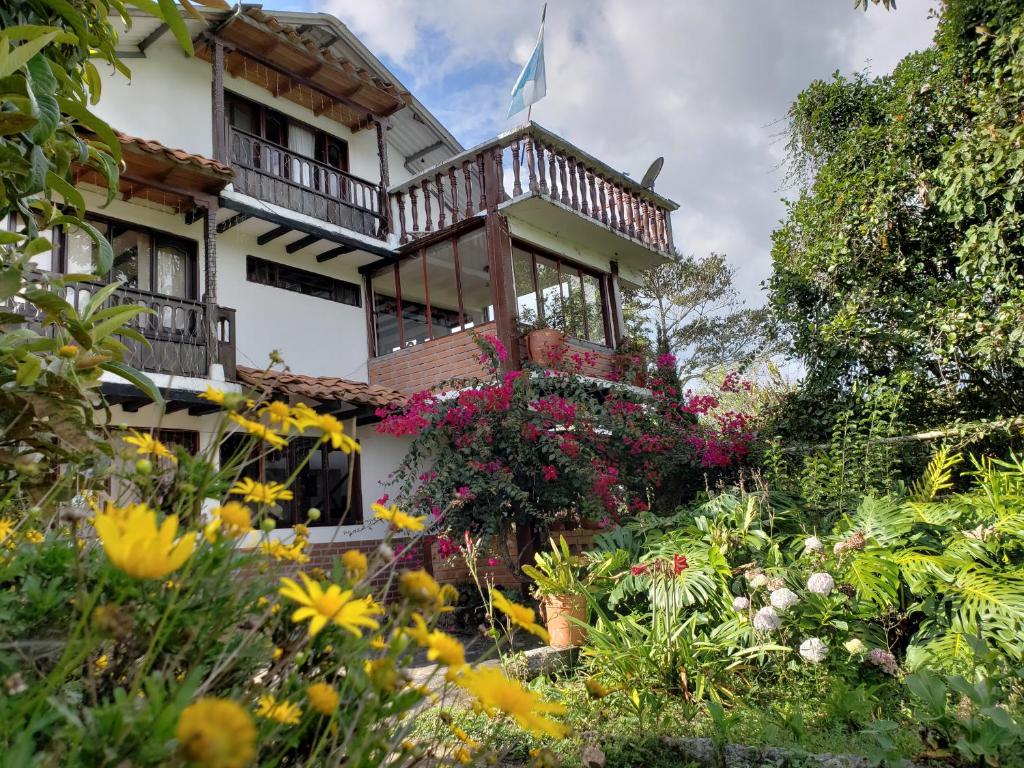 une maison avec un jardin fleuri devant elle dans l'établissement Hostal Pachamama, à San Agustín