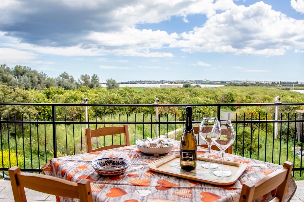 uma mesa com uma garrafa de vinho e copos numa varanda em Casa Abela em Siracusa