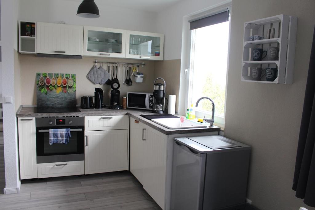 a kitchen with white cabinets and a sink and a window at Schöne 54qm Fewo nahe Rostock und Warnemünde in Lambrechtshagen