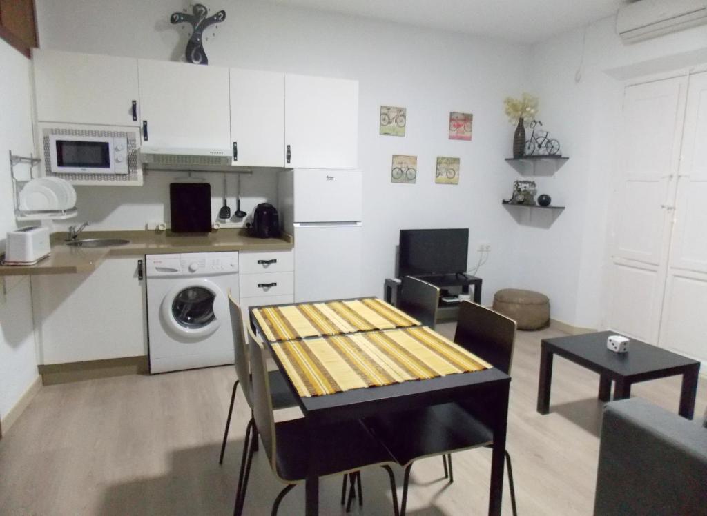 a small kitchen with a table and a dining room at Apartamentos Capuchinas in Plasencia