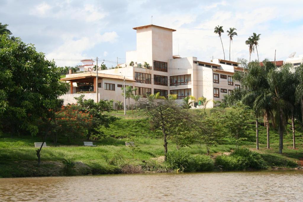 a large white building next to a body of water at Hotel Vila das Palmeiras in Altinópolis