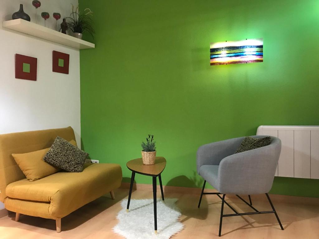 Habitación verde con sofá, silla y mesa. en Apartamento en Corrala, en Madrid