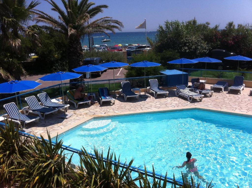 a beach with a pool, chairs, and a pool table at Cit'Hotel Hostellerie de la Nartelle in Sainte-Maxime