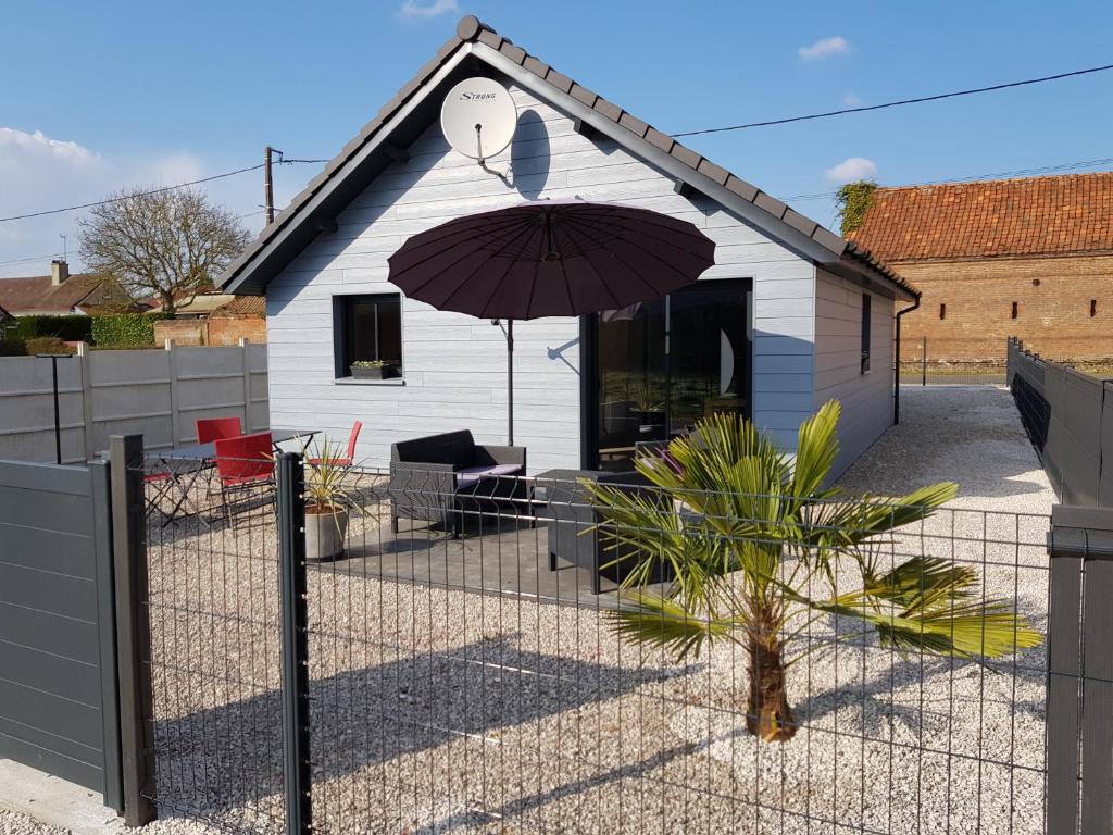 a fence with an umbrella in front of a house at Le Chalet de l'Authie in Saulchoy