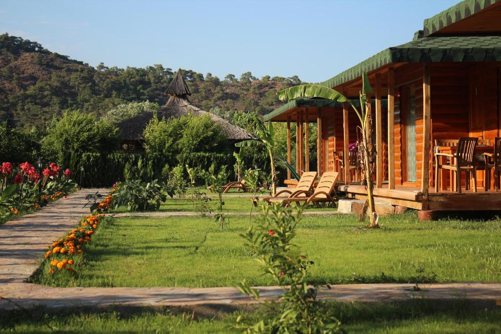 eine Veranda einer Hütte mit Stühlen und Blumen in der Unterkunft Cirali Armira Bungalow in Cıralı