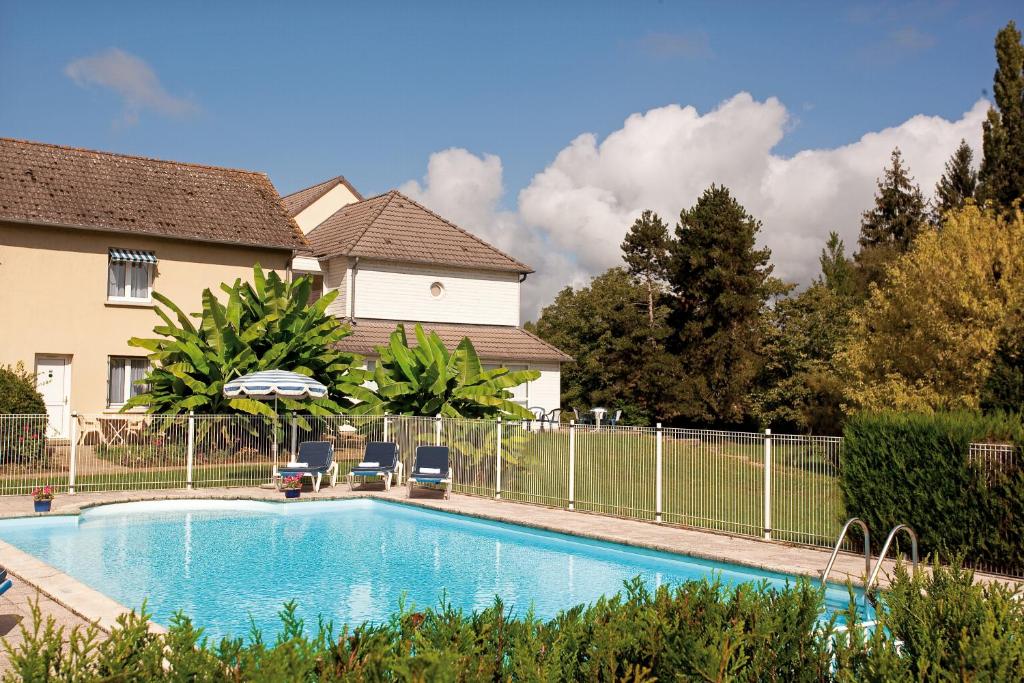 a swimming pool in a yard next to a house at Logis Hôtel du Pont Neuf in Le Veurdre