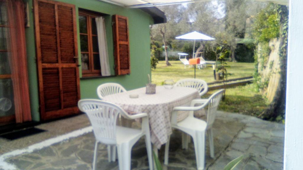un tavolo con sedie bianche e un ombrellone su un patio di Lo Chalet tra gli ulivi a Santa Margherita Ligure