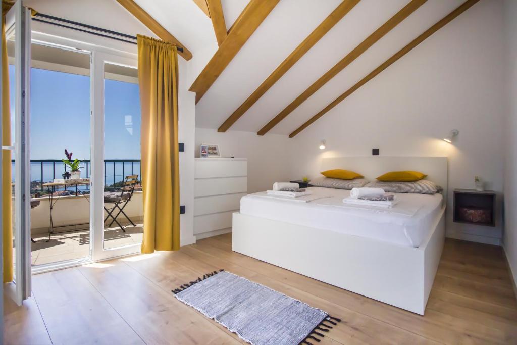 a bedroom with a large white bed and a balcony at Holiday House Kleme in Makarska
