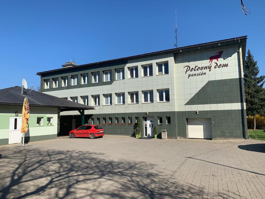 un edificio con un coche rojo estacionado frente a él en Poľovný dom, en Jelšava