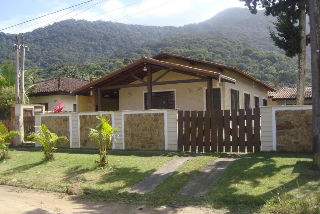 une maison avec une clôture en face d'une montagne dans l'établissement CASA ESPAÇOSA 4 DORMITÓRIOS A 150M DA PRAIA DA MARANDUBA / UBATUBA, à Ubatuba
