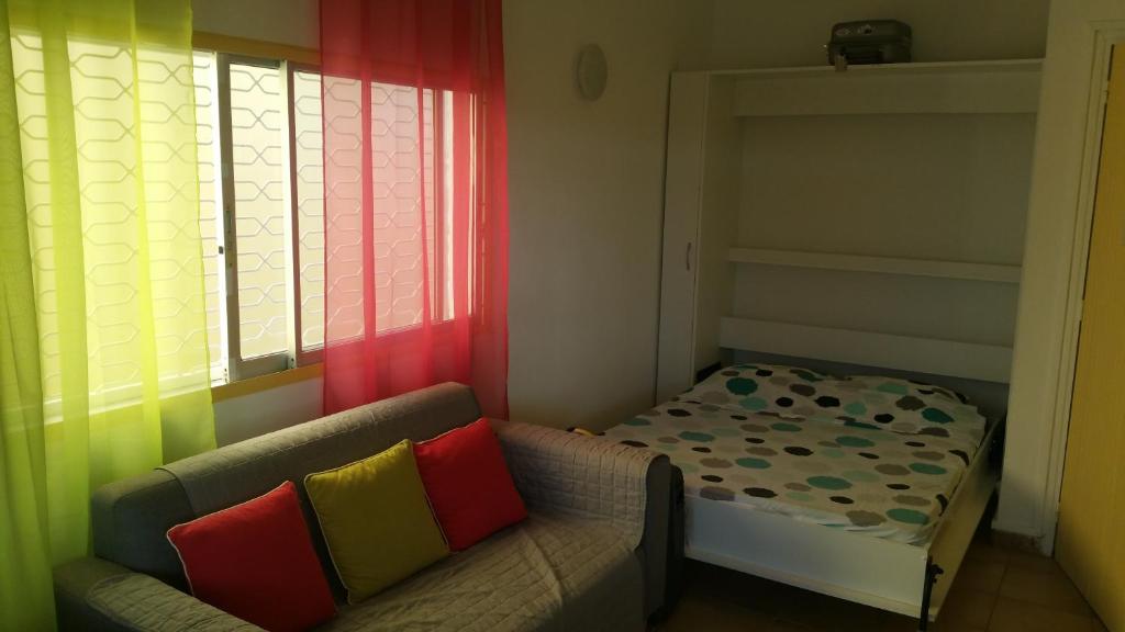a small room with a couch and a bed at le petit coin de paradis in Sainte-Anne