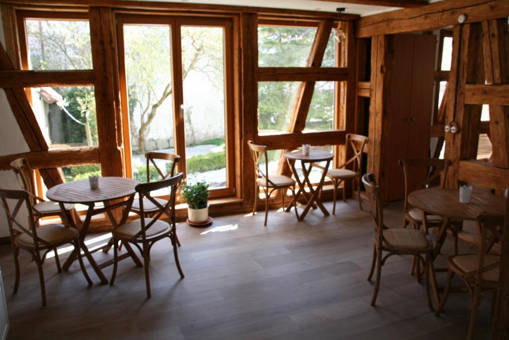 een kamer met tafels, stoelen en ramen bij Waldvogel Ferienzimmer klimatisiert in Immenstaad am Bodensee