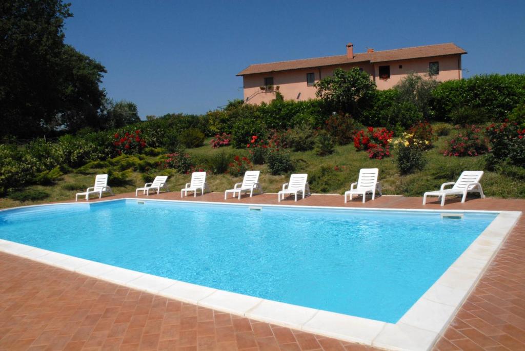 a swimming pool with chairs and a house in the background at L'Antico Casale Di Sandro in Acquasparta