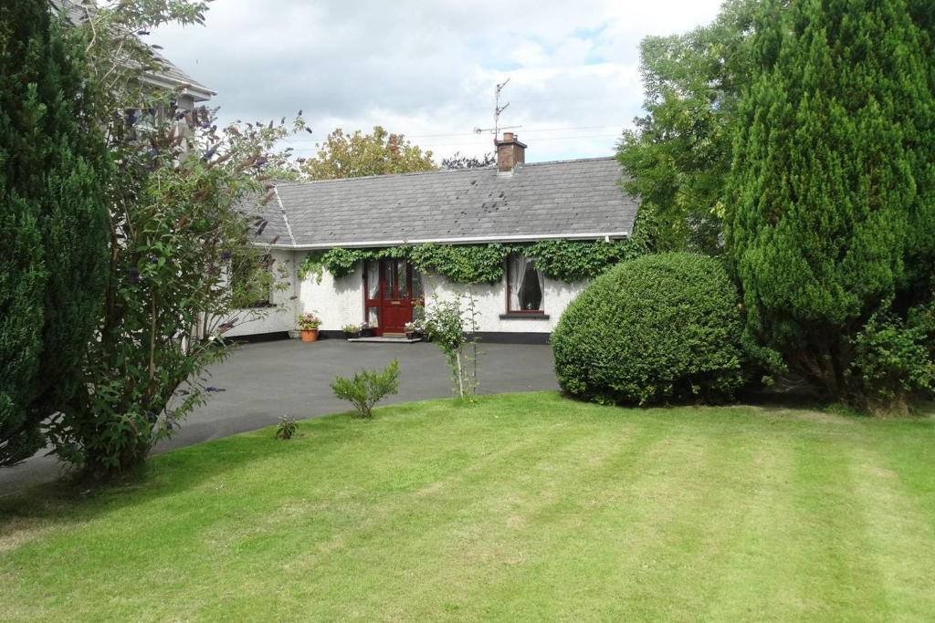 una casa blanca con una puerta roja y un patio en Moyola River Cottage, en Magherafelt