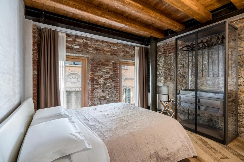 a bedroom with a bed and a brick wall at Crocus Apartments in Sirmione