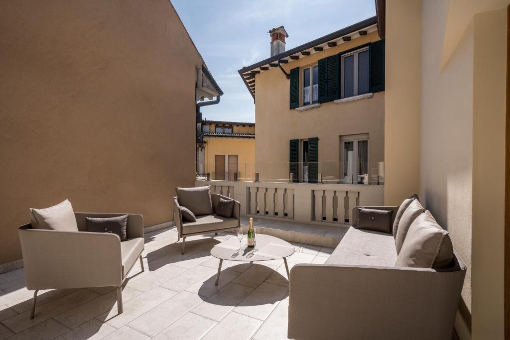 patio z kanapami i stołem na balkonie w obiekcie Crocus Apartments w Sirmione