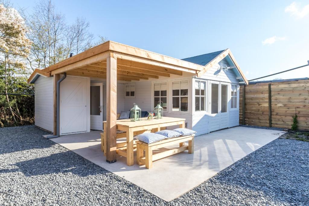 eine hölzerne Pergola mit einem Tisch und einer Bank auf einer Terrasse in der Unterkunft George's Lodges Renesse in Renesse