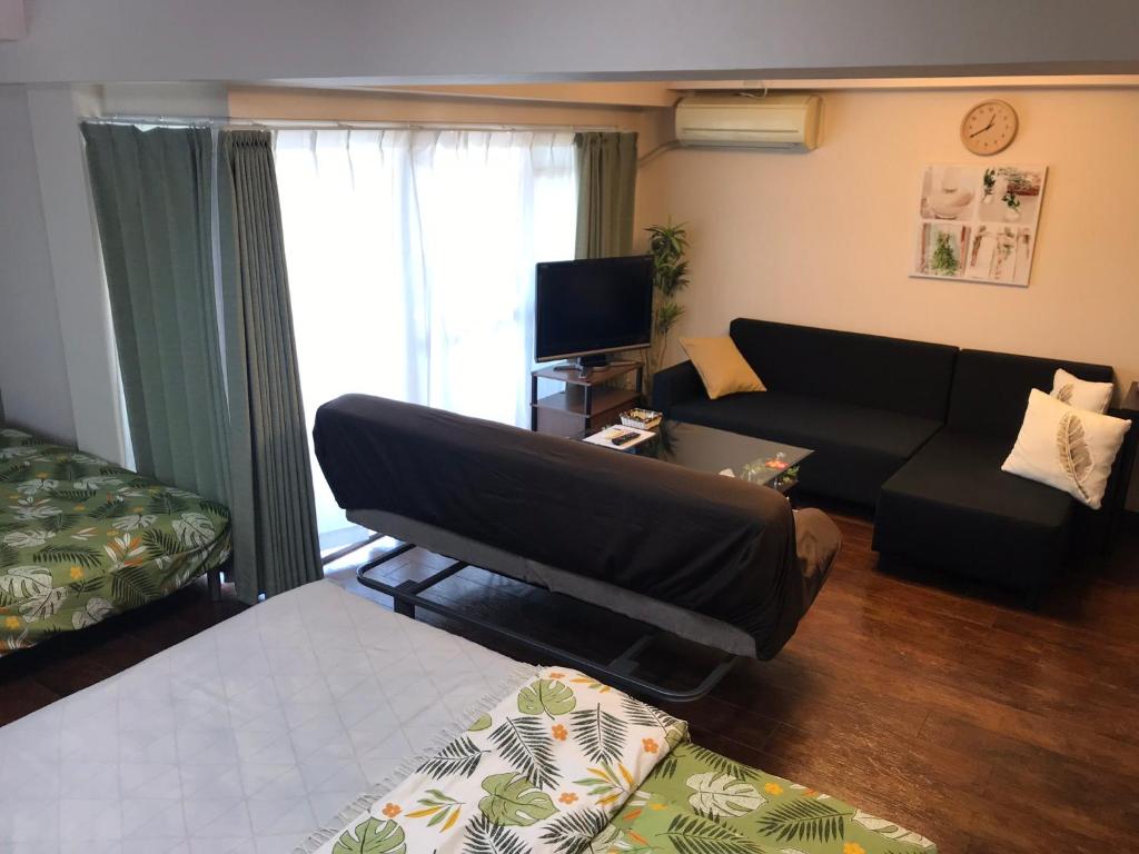 a living room with a black couch and a television at Lipelala Stay 505 in Osaka