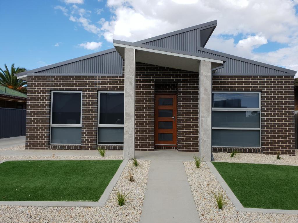 a brick house with a red door and grass at Wimmera Plains in Horsham