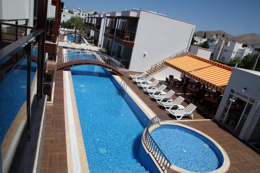 a hotel with a swimming pool with chairs and a bridge at Siesta Garden Apart Hotel in Turgutreis