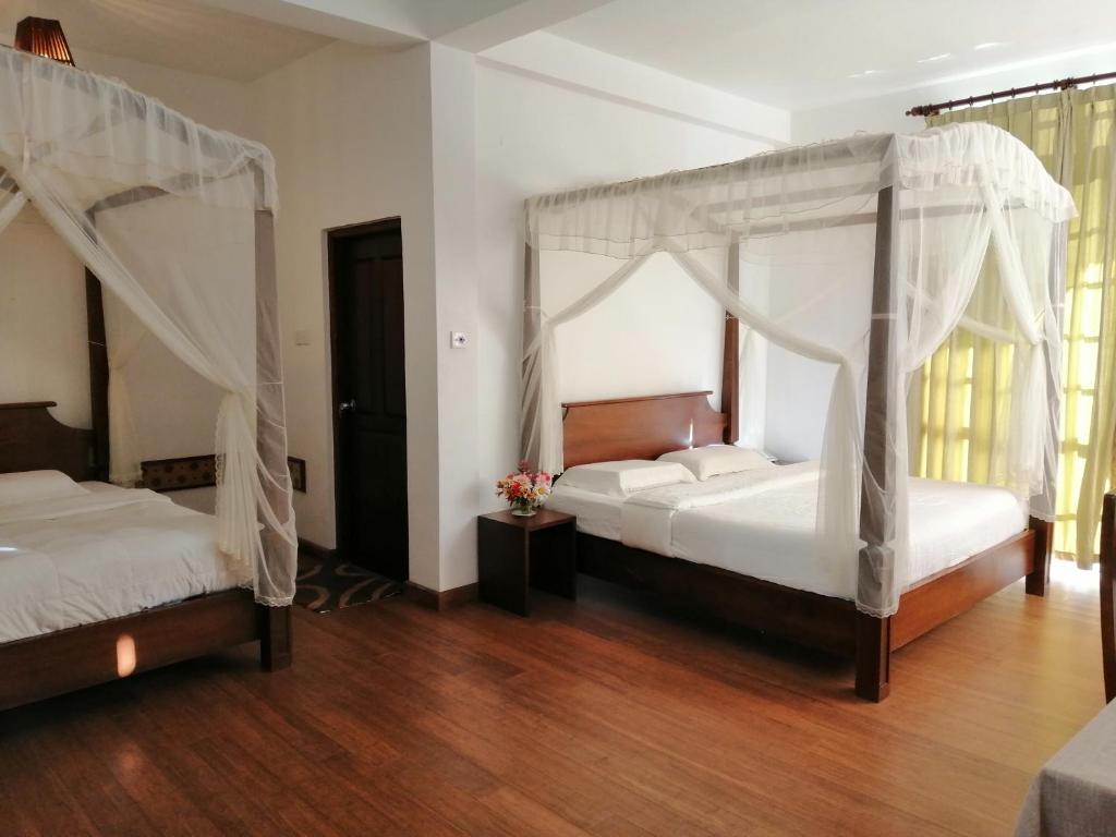 two beds in a room with wooden floors at Melford Nuwaraeliya in Nuwara Eliya