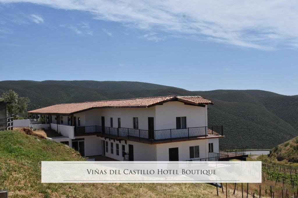 une maison blanche sur une colline avec des montagnes en arrière-plan dans l'établissement Viñas del Castillo, à Ensenada