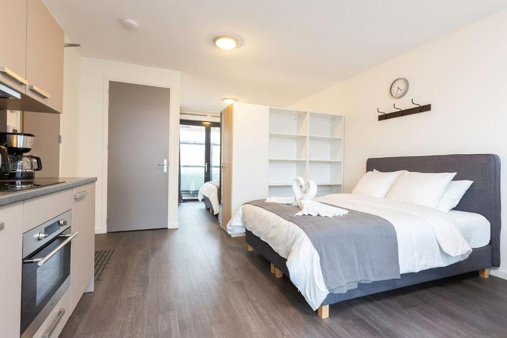 a bedroom with a large bed and a kitchen at New Loft Apt View Delft city center balcony Utopia2c in Delft