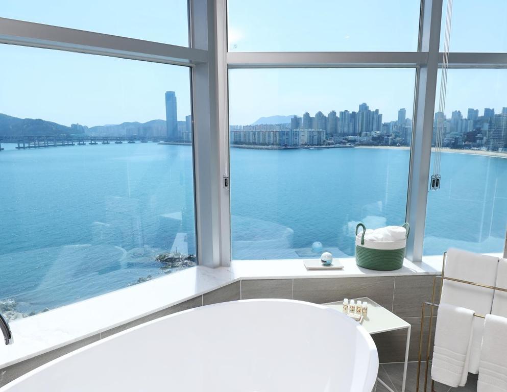 a bathroom with a bath tub and a large window at H Avenue Gwanganri Beach in Busan