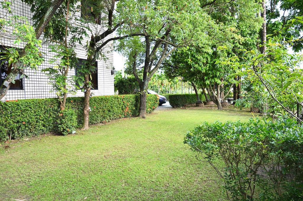 a yard with green grass and trees and a house at Kaohsiung Meinong Rabbit Paul Homestay B&amp;B in Meinong