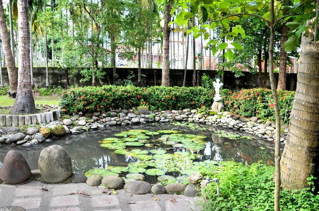 a garden with a pond with a statue in it at Kaohsiung Meinong Rabbit Paul Homestay B&amp;B in Meinong