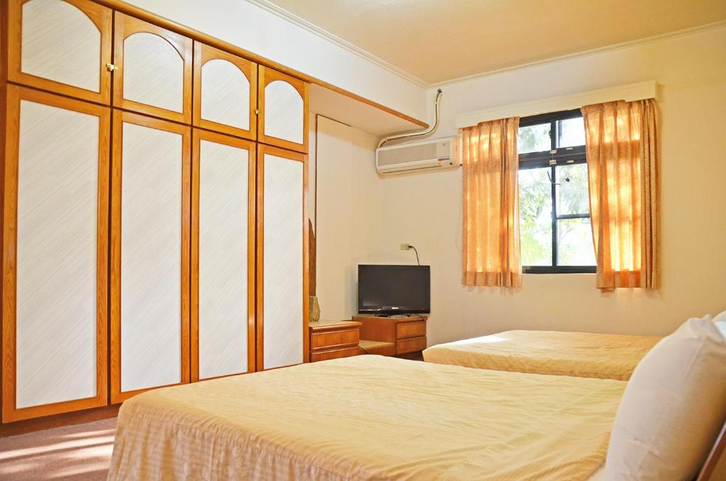 a hotel room with two beds and a television at Kaohsiung Meinong Rabbit Paul Homestay B&amp;B in Meinong