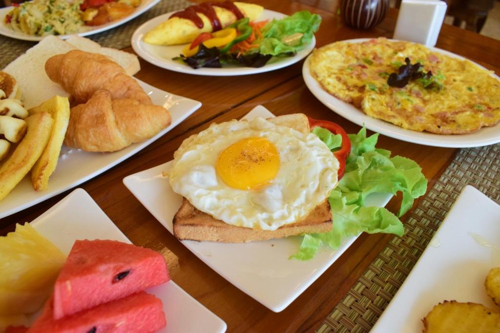 a table with plates of breakfast foods on them at Villa Sirilanna Hotel in Chiang Mai